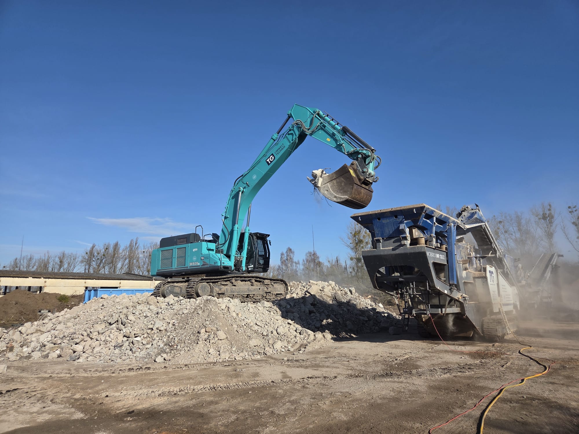 Recycling & Kreislaufwirtschaft – Bagger an Brechanlage TG-Bagger beschickt eine Brechanlage mit Bauschutt